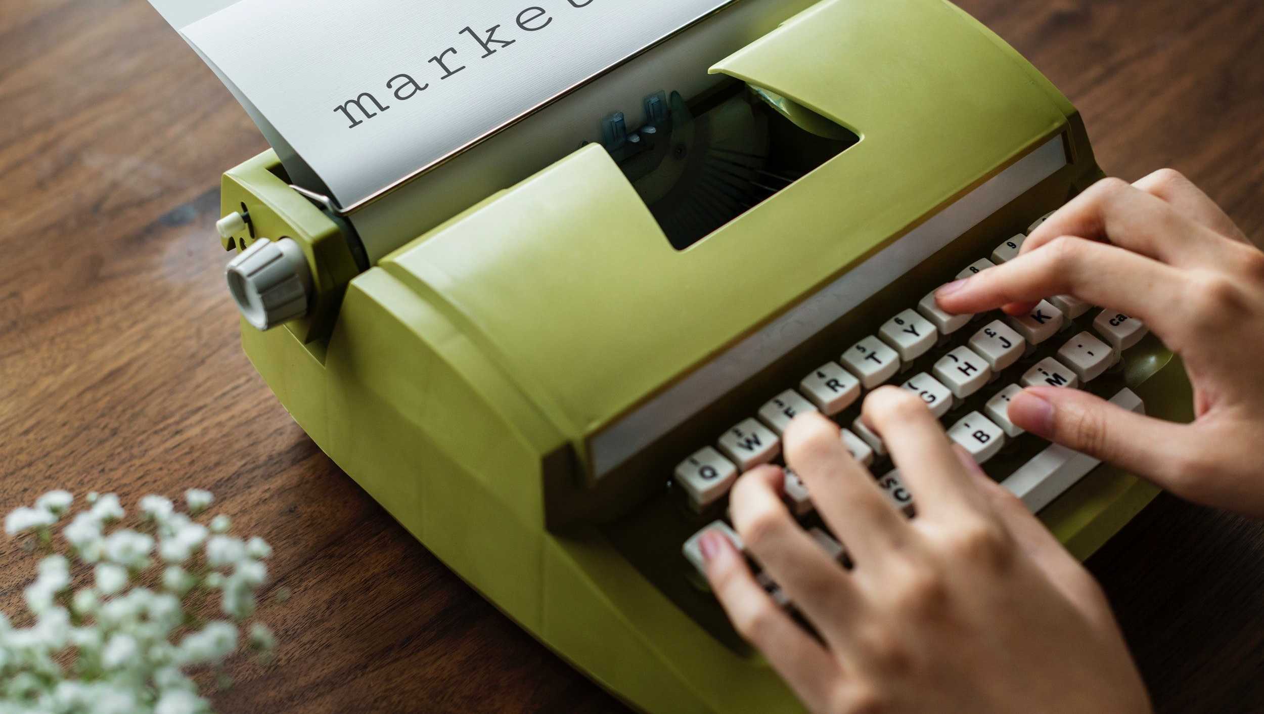 Image of a person typing marketing on a typewriter.